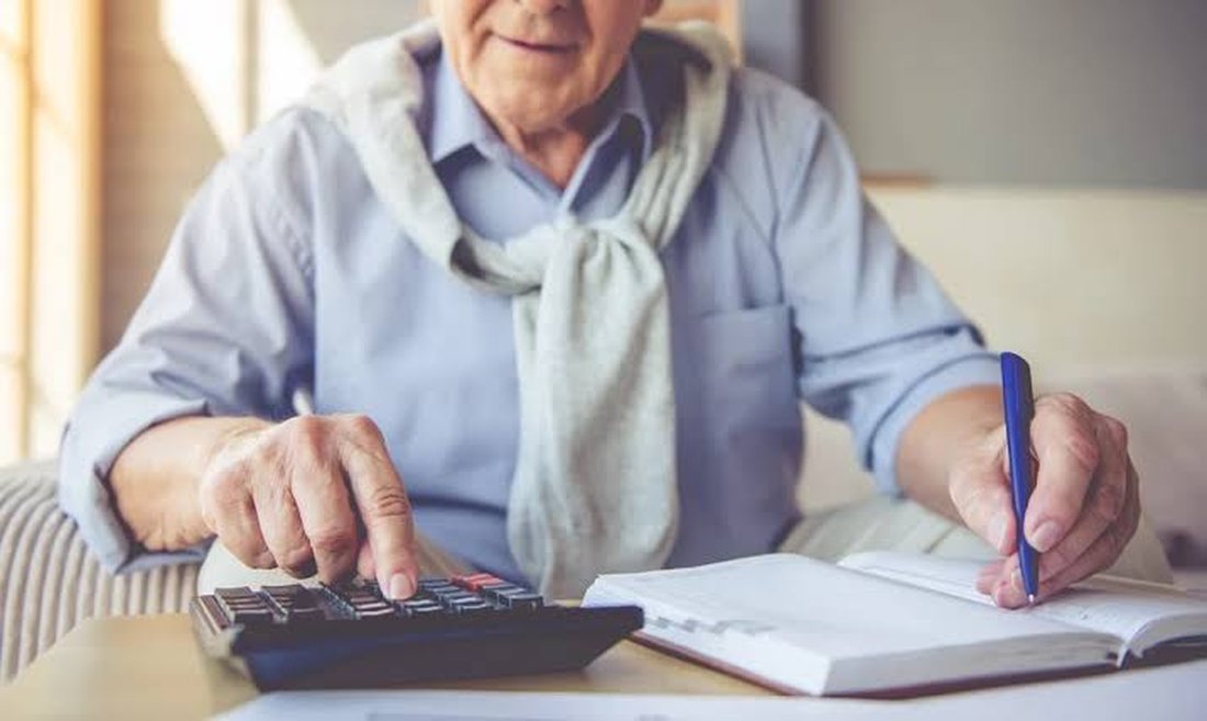 Aposentado calculando valores em casa, ilustrando a revisão de aposentadoria